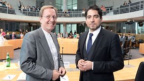 Zwei Männer stehen in einem großen Anhörungssaal