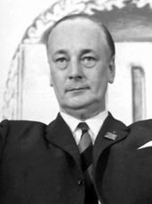 Schwarz-weiße Fotografie eines Mannes mit streng gekämmten Haaren und tiefen Augenringen