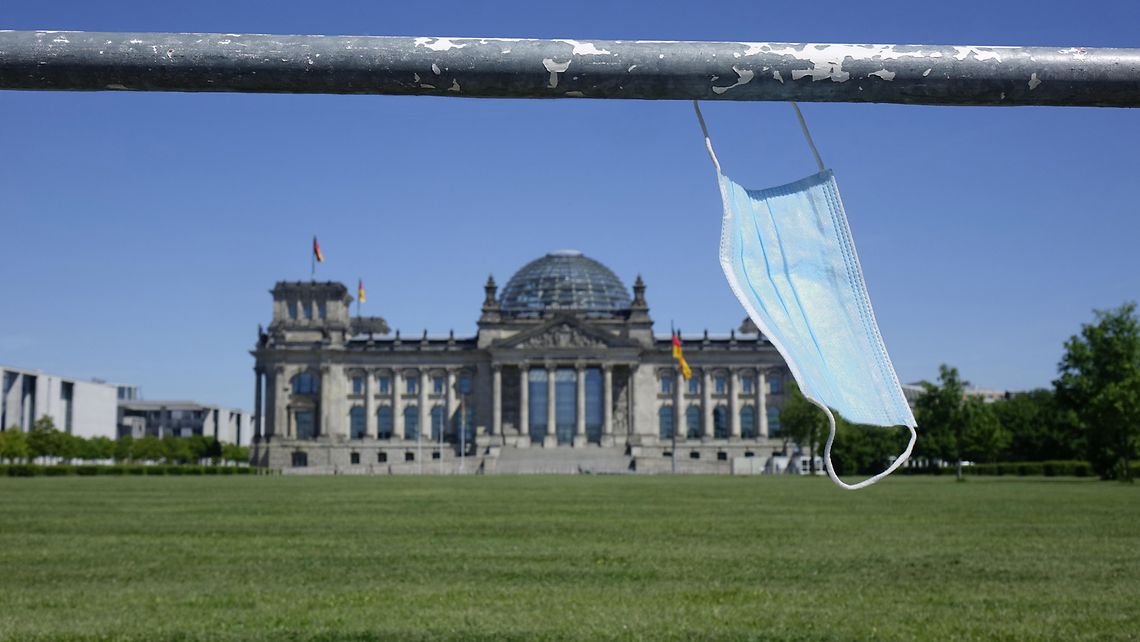 Vor dem Reichstagsgebäude hängt an einer Absperrung eine Mundschutzmaske.